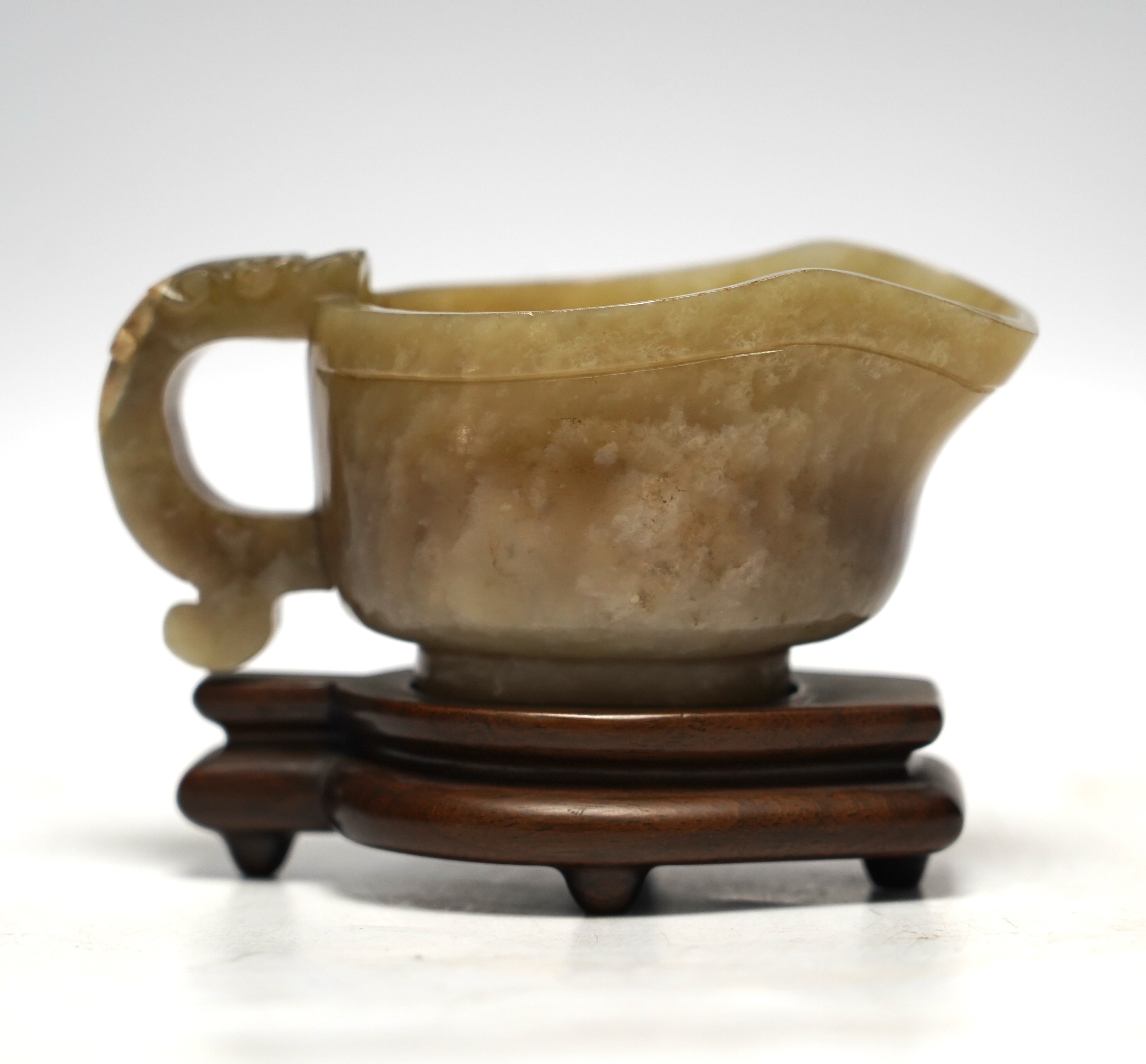An 18th century Chinese archaistic jade pouring vessel, yi, with carved dragon handle, 6cm high, on a hardwood stand